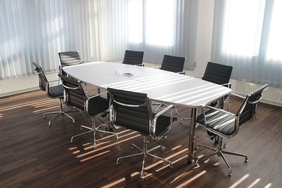 A meeting room with empty chairs around an oval table