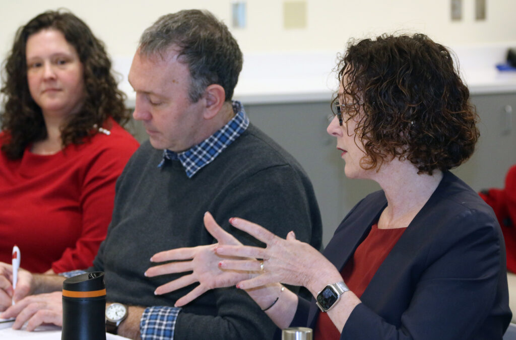 Three people including US Representative Val Hoyle sitting at a table during a meeting