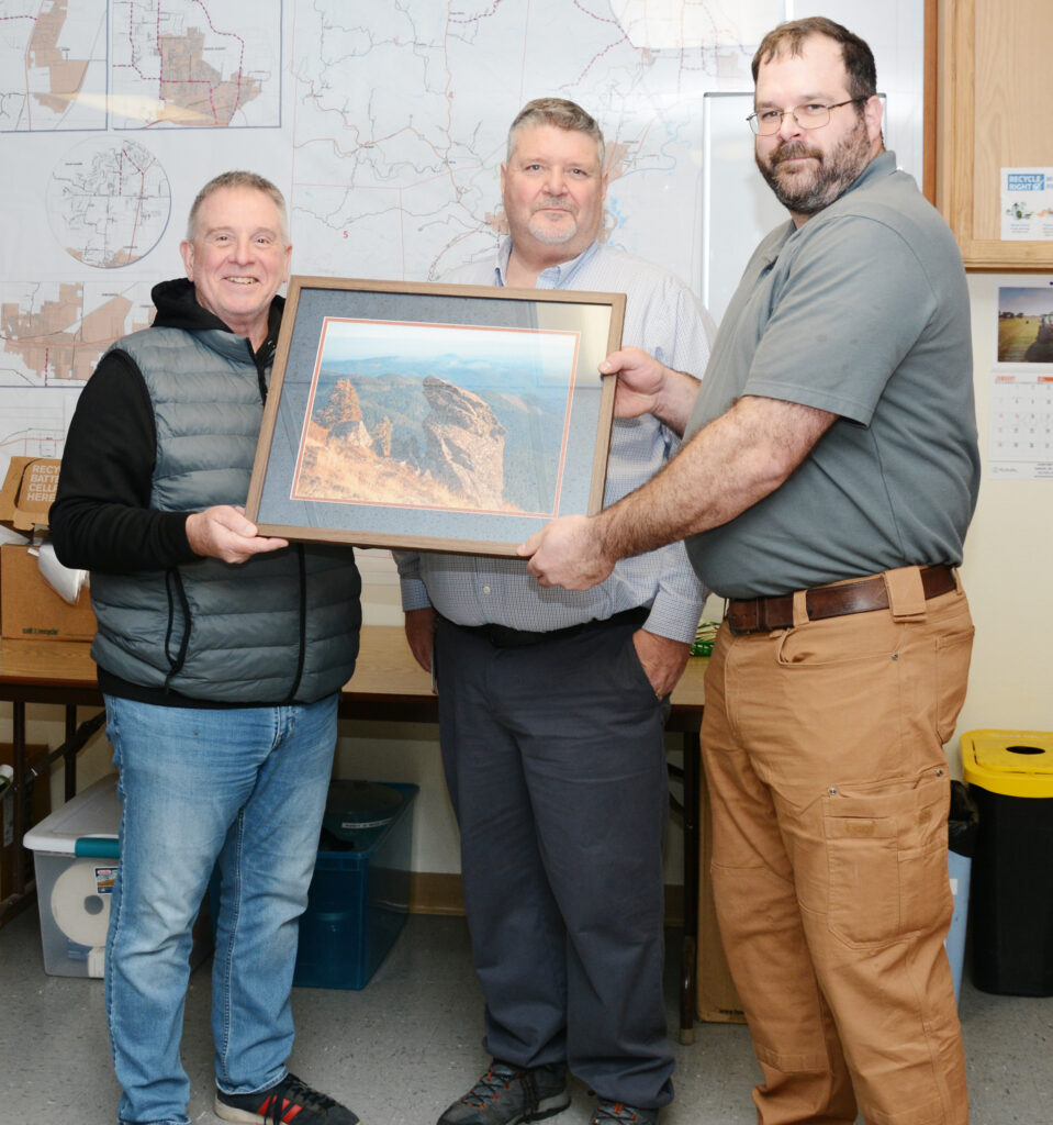 Public Works Director Gary Stockhoff and Facilities Manager Paul Wallsinger present Matt Hertel with a challenge coin and photo.