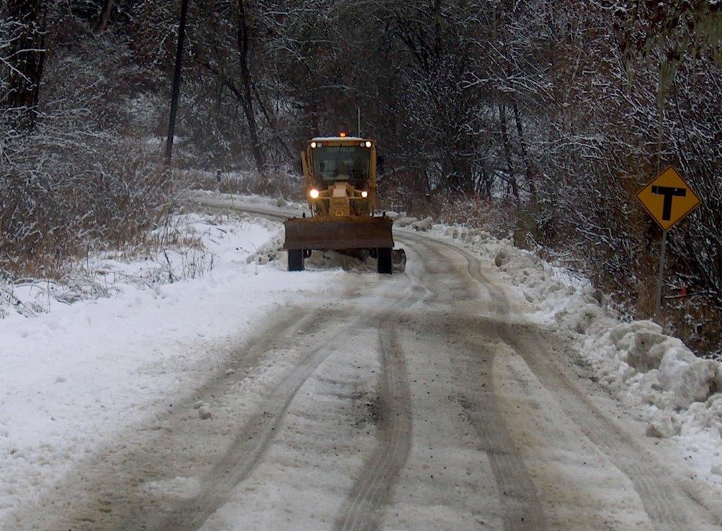 A road grader plows snow on a Benton County road.