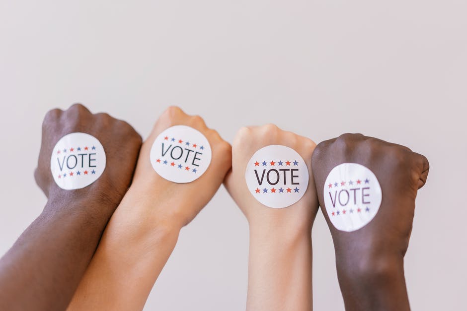 White vote stickers are placed on the back of Black and white hands.