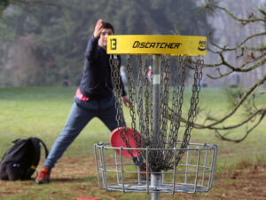 disc golf player with basket in foreground